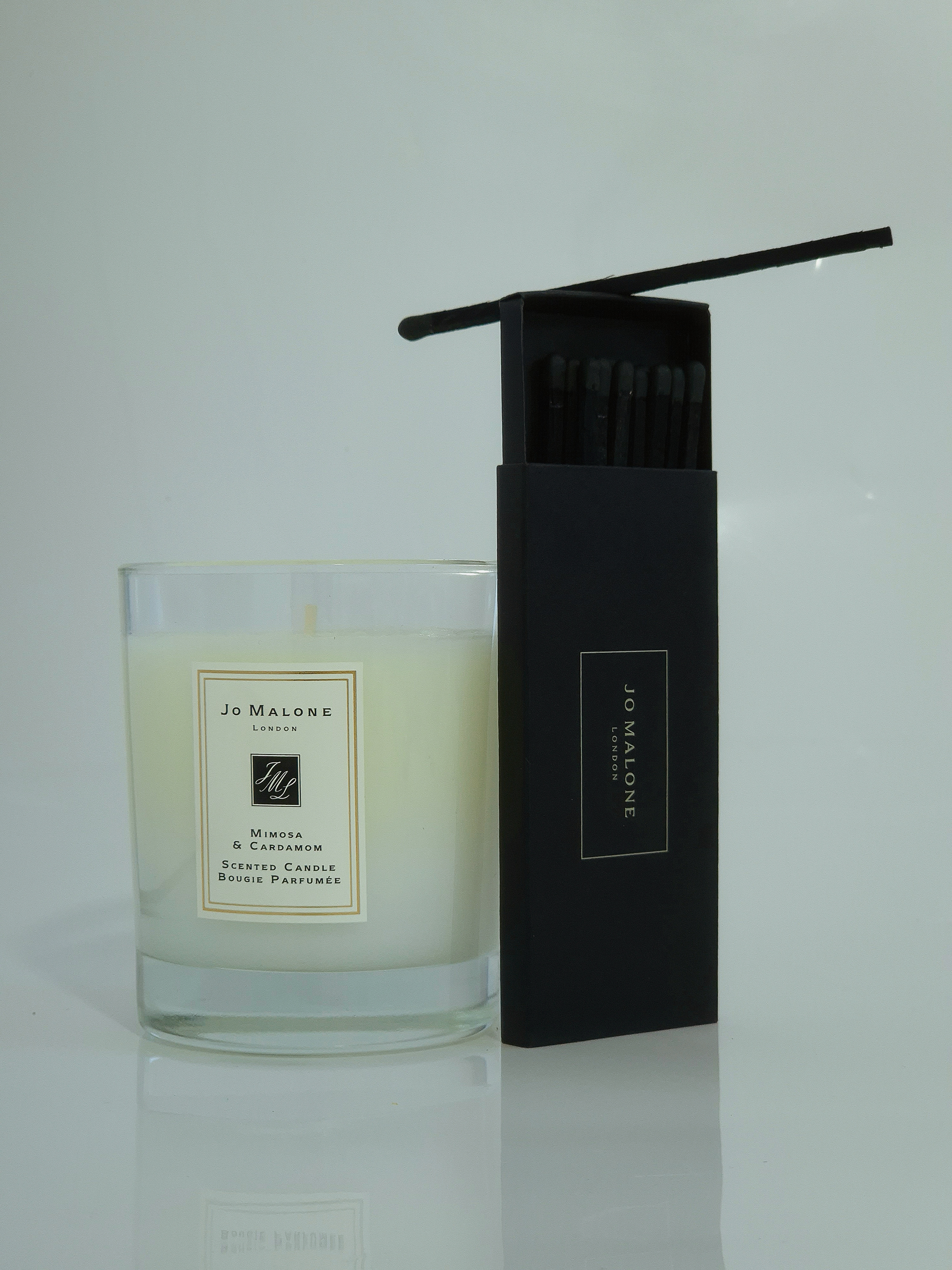 Scented candle beside an open box of black matches on a white surface.