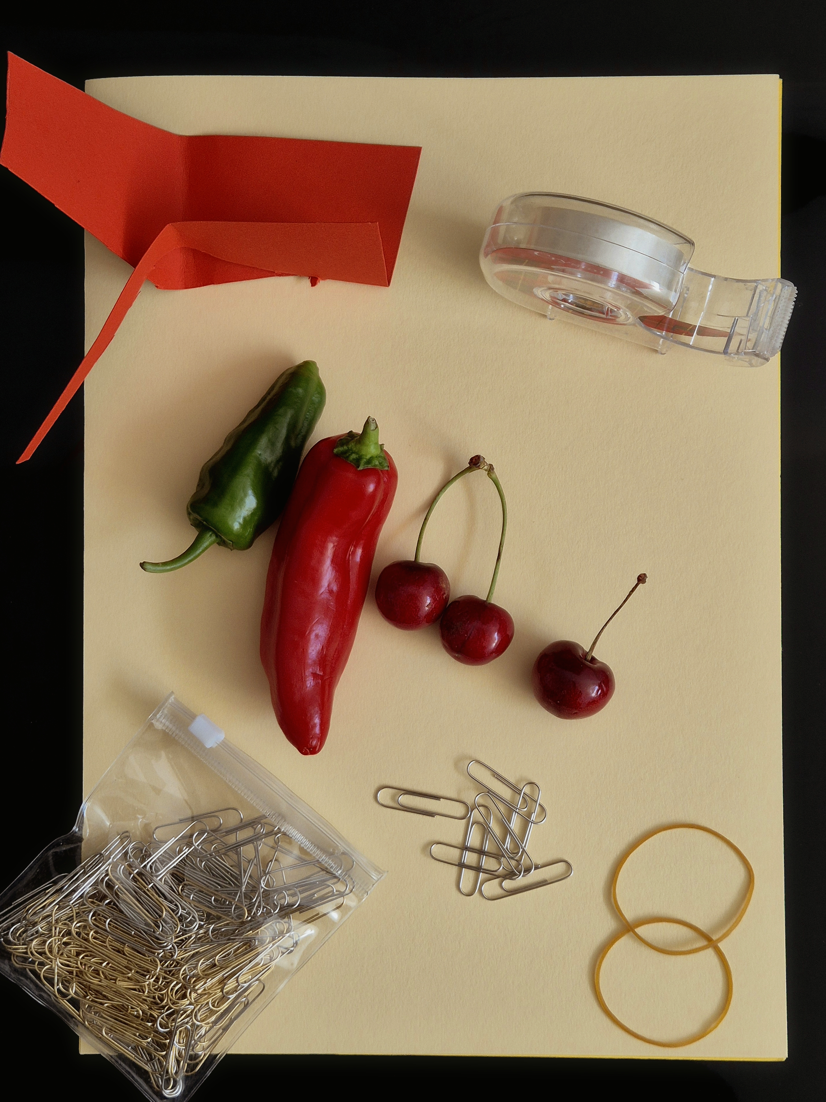 A playful still life by IVRIEL where peppers, paper and everyday desk objects become sculptural gestures of colour, balance and quiet poetry.