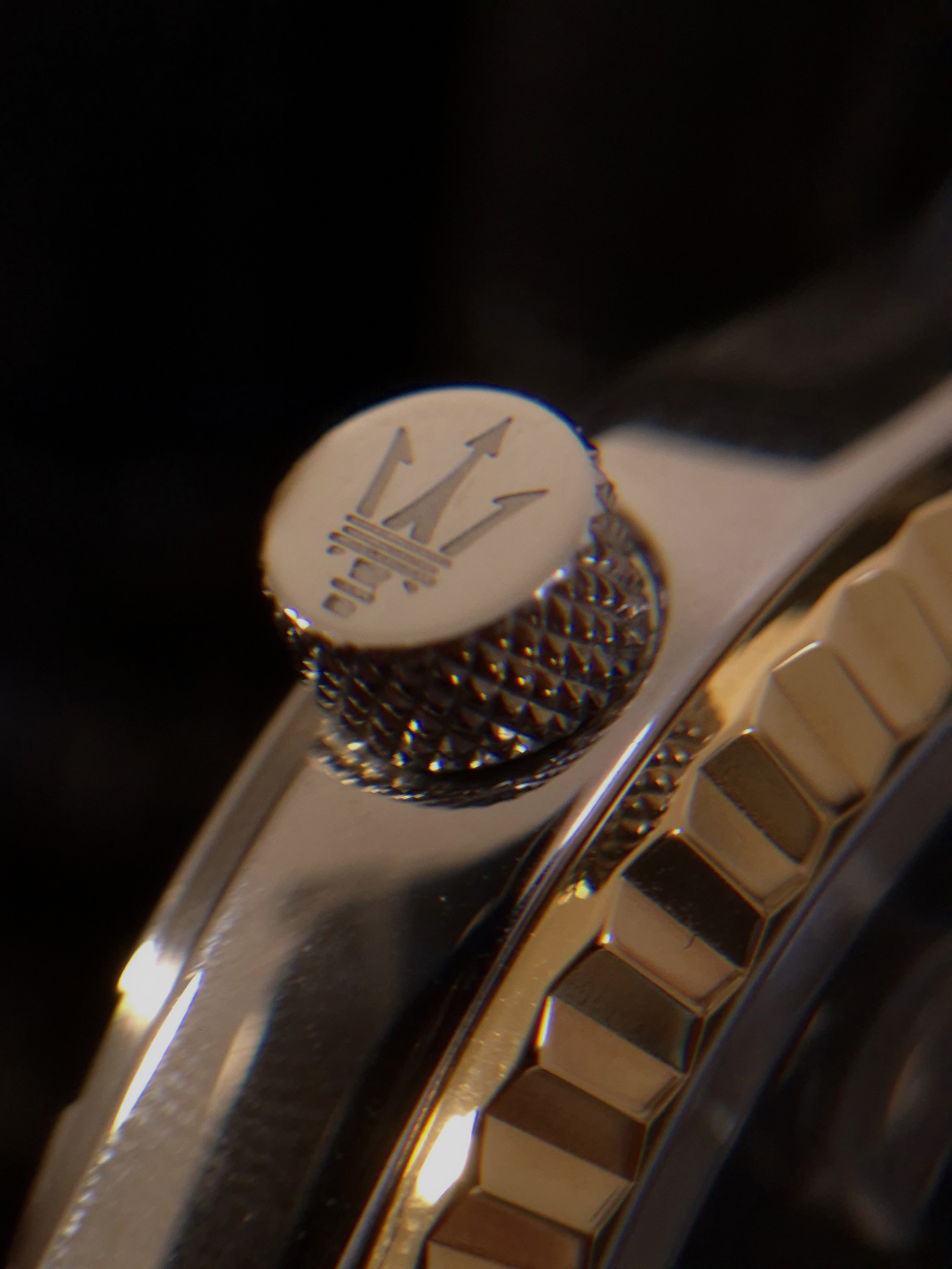 Macro shot of the Maserati watch crown engraved with the trident logo.