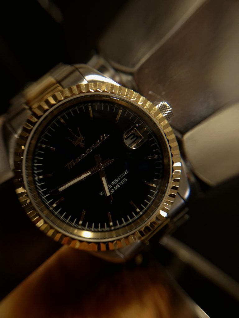 Macro close-up of a wristwatch showing gold details and reflections from the moka pot.